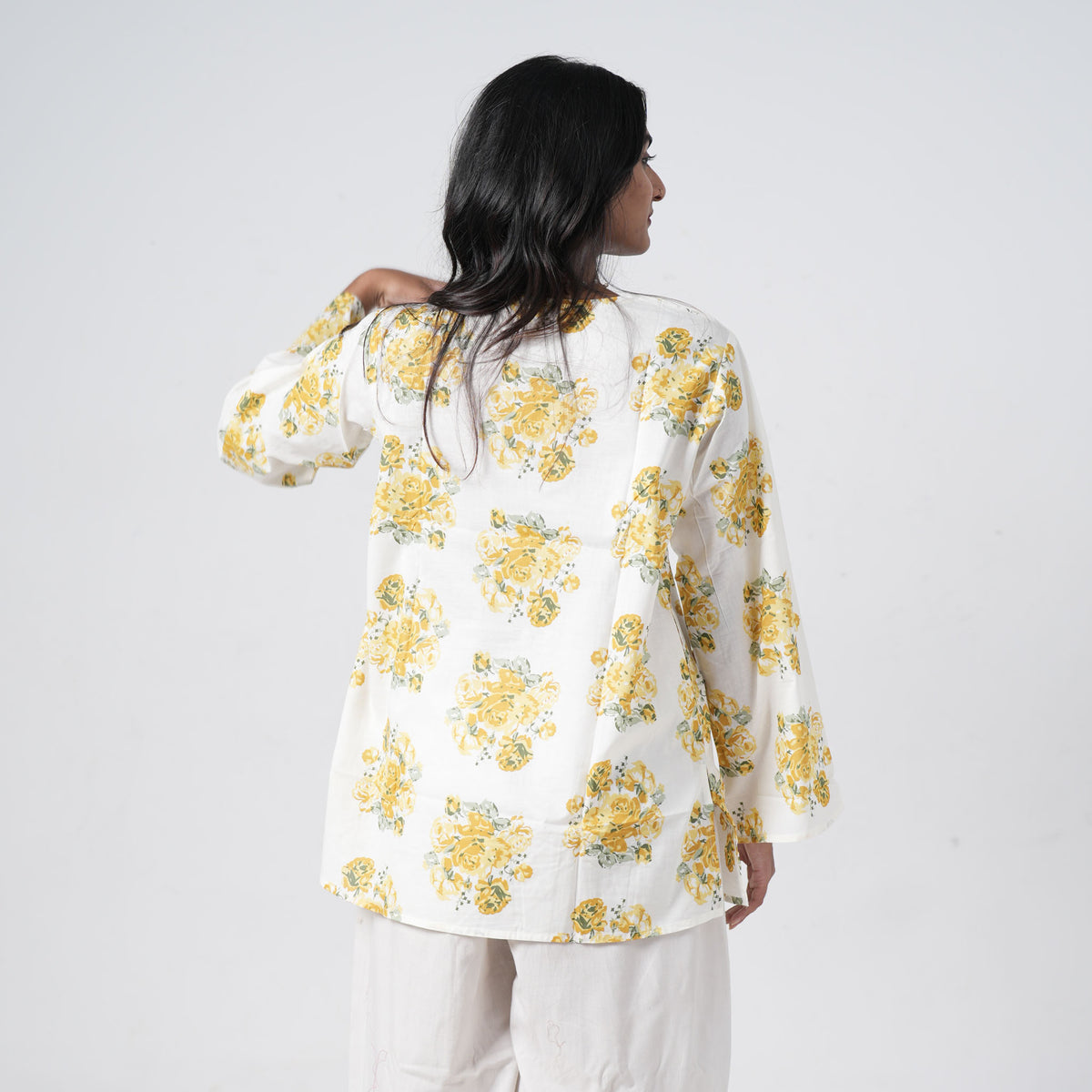 Back view of yellow floral short kurti with yellow rose prints on a white base